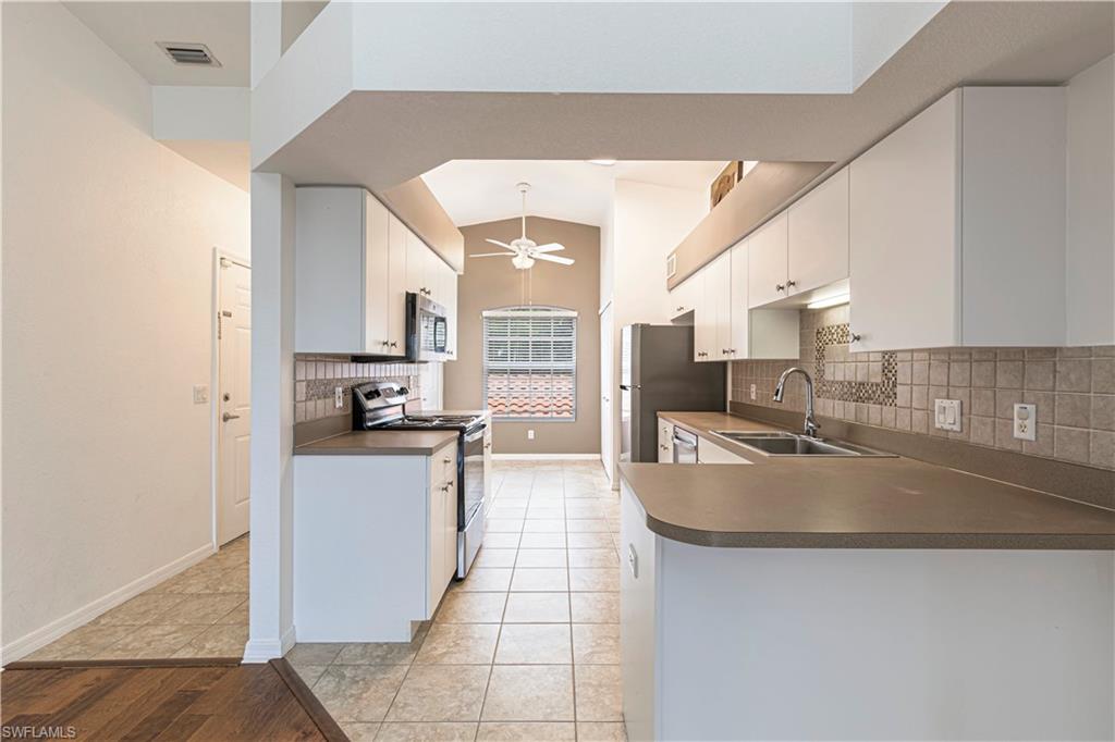 Kitchen featuring white cabinetry, gray countertops, stainless steel appliances, and a tiled backsplash