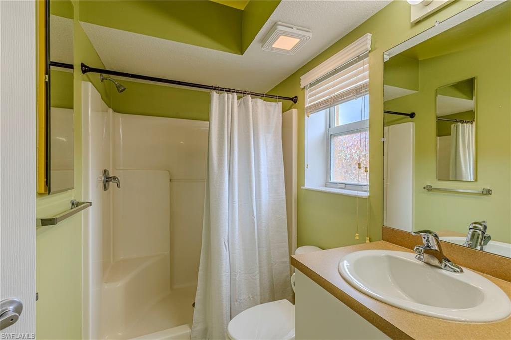 Primary Bathroom featuring a shower/tub combination, single vanity with laminate countertop, chrome fixtures, and a window with blinds