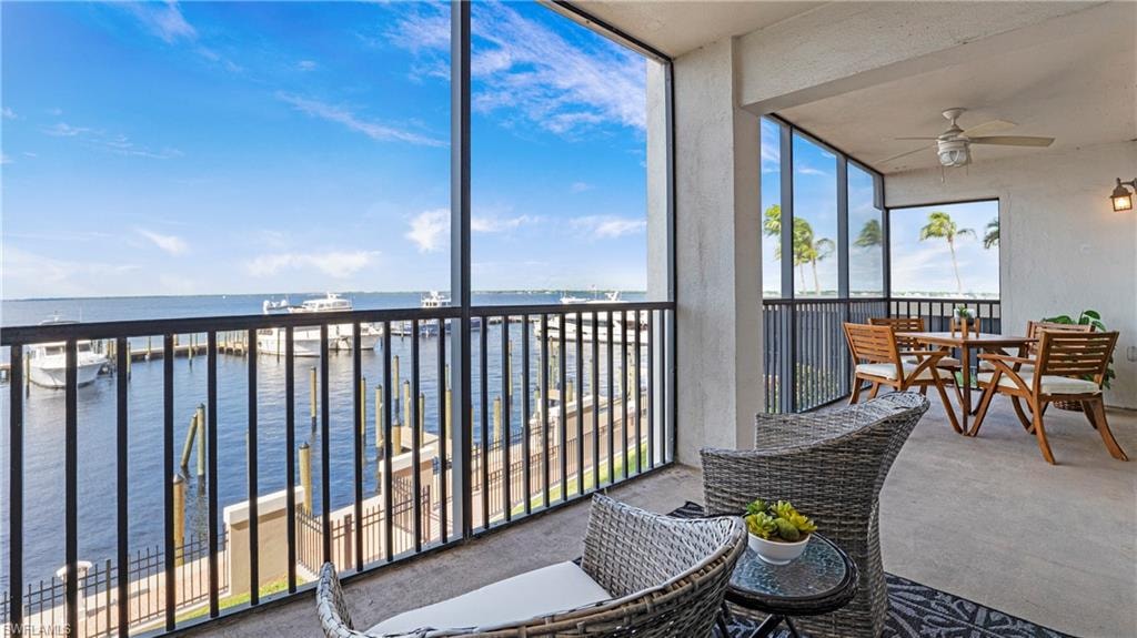 Sunroom / solarium featuring a water view, ceiling fan, and a balcony