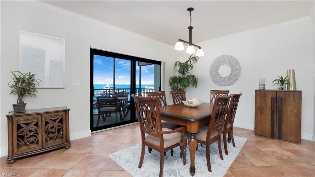 Dining space with ornamental molding, a water view, and light tile patterned flooring
