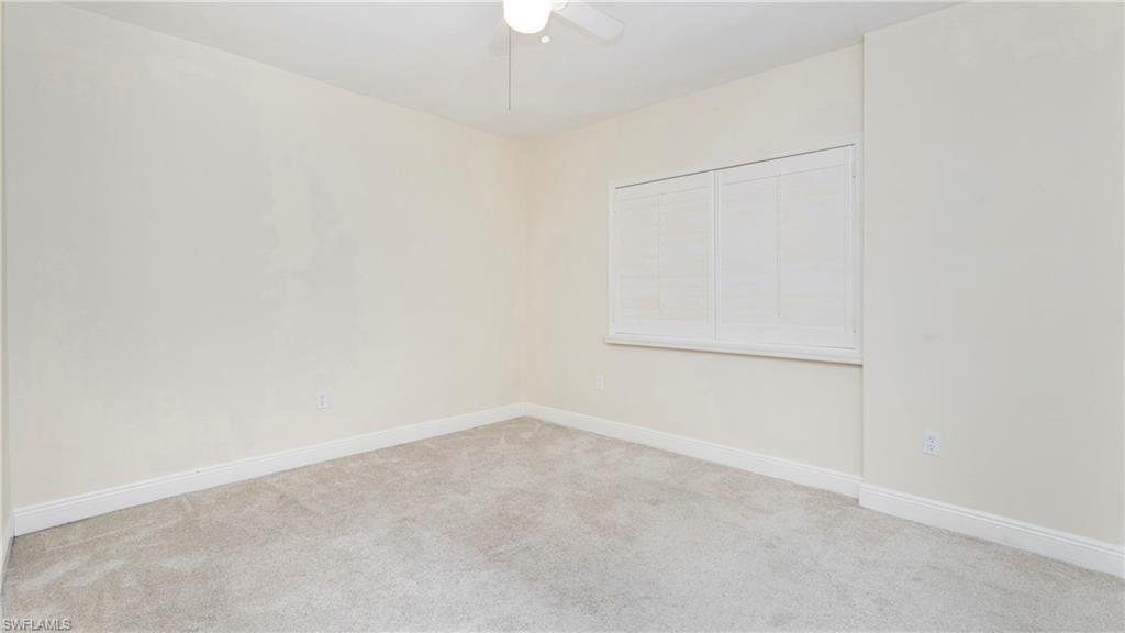 Carpeted empty room featuring baseboards and ceiling fan