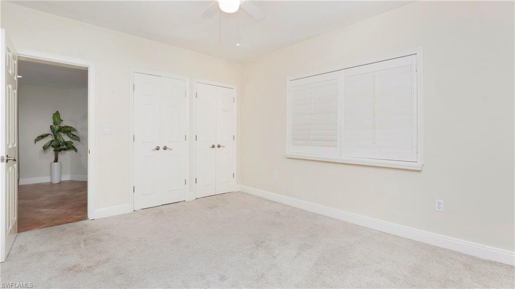 Unfurnished bedroom with two closets, carpet flooring, and a ceiling fan