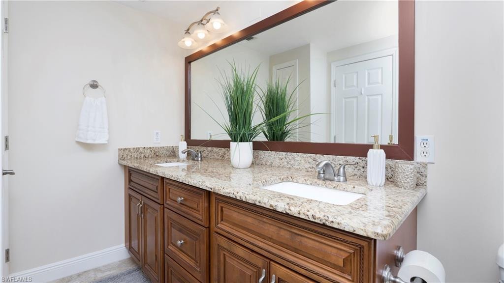 Full bath featuring double vanity and baseboards