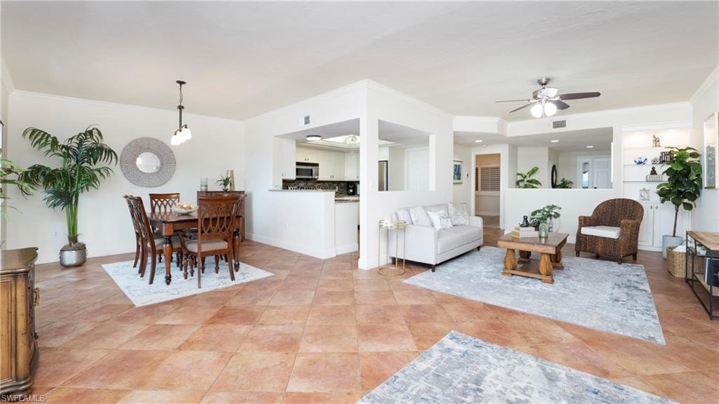 Living room featuring crown molding, ceiling fan, and light tile patterned floors