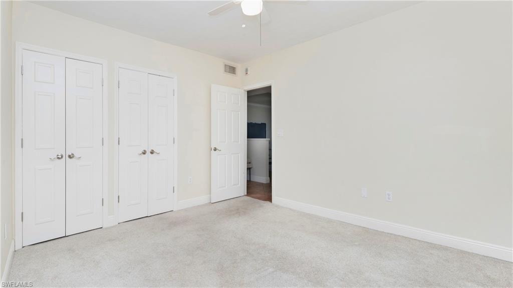 Unfurnished bedroom with carpet, multiple closets, and a ceiling fan
