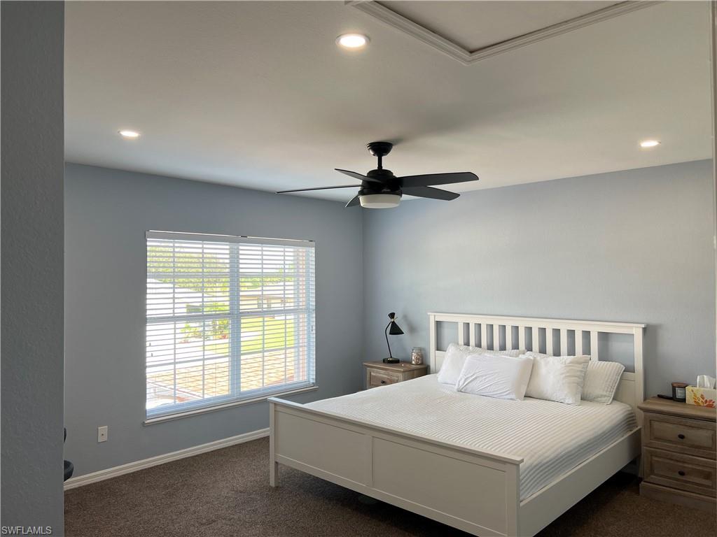 Spacious bedroom featuring light blue walls, recessed lighting, a ceiling fan with integrated light, and a large window with horizontal blinds