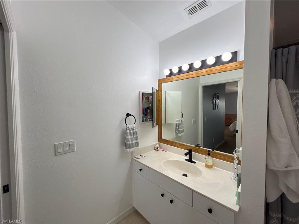 Bathroom vanity featuring a quartz-finish countertop, undermount sink, and matte black faucet