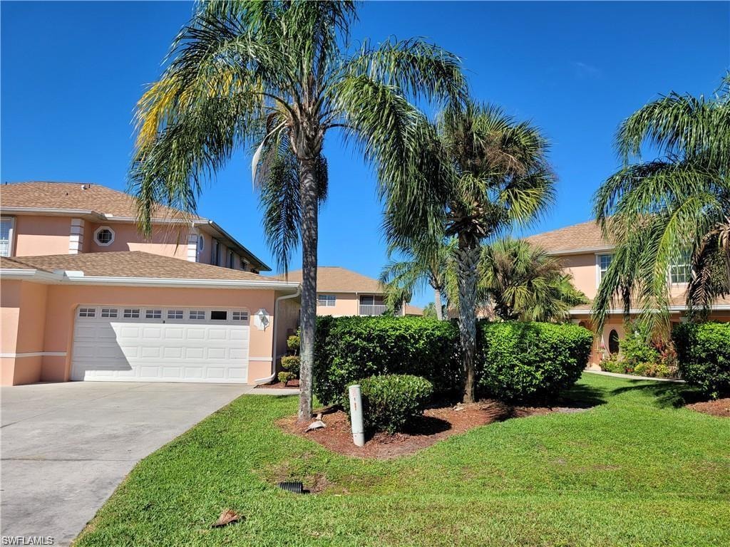 Residential property featuring a two-car garage, concrete driveway, and mature landscaping