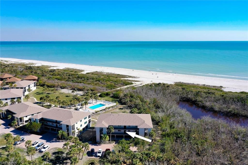 Coastal community featuring multi-story buildings with balconies, a swimming pool, and direct beach access