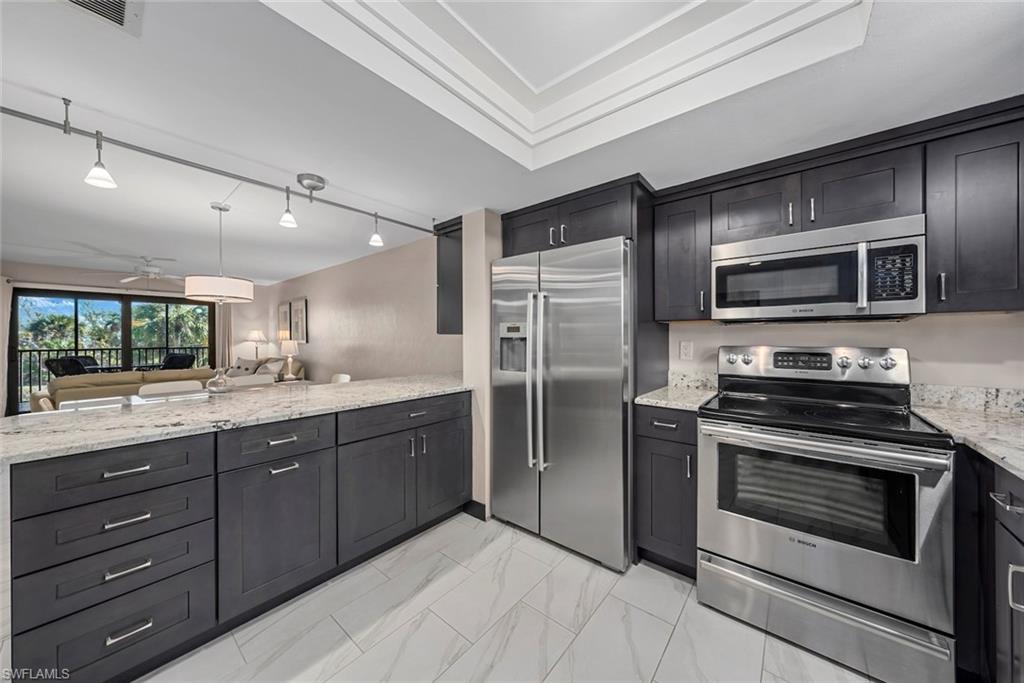 Modern kitchen featuring dark wood cabinetry, light-toned countertops, and stainless steel appliances