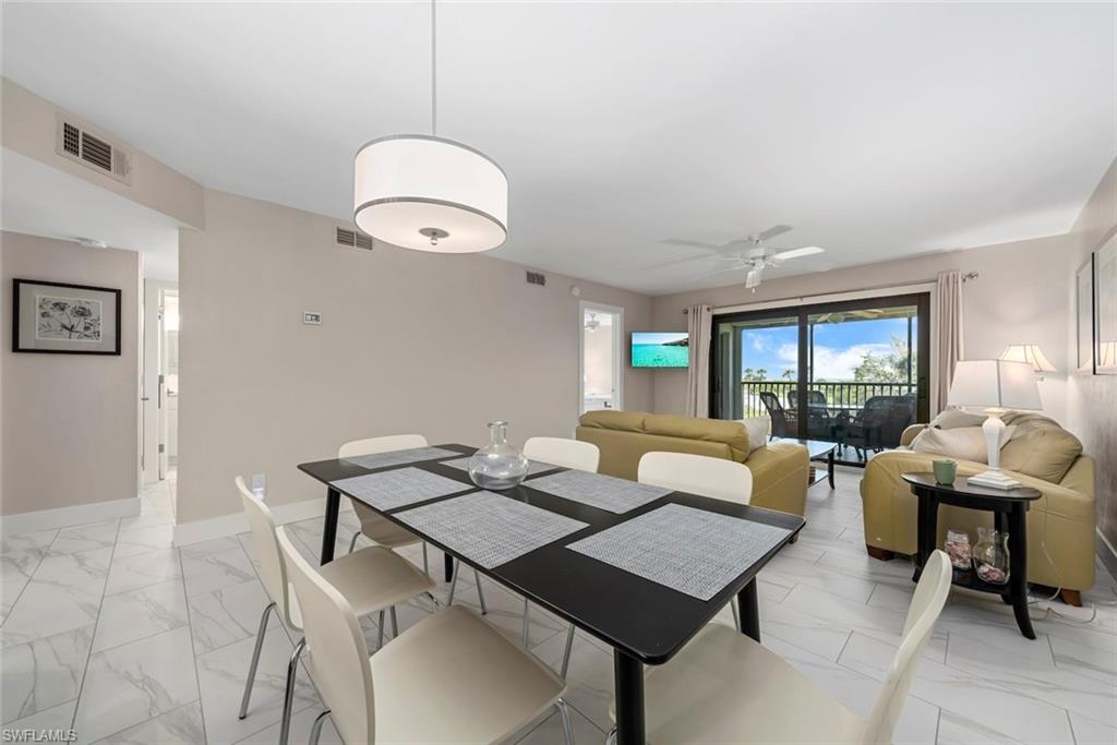 Open-concept living and dining area featuring large format tile flooring, a contemporary drum chandelier, and sliding glass doors leading to an outdoor space