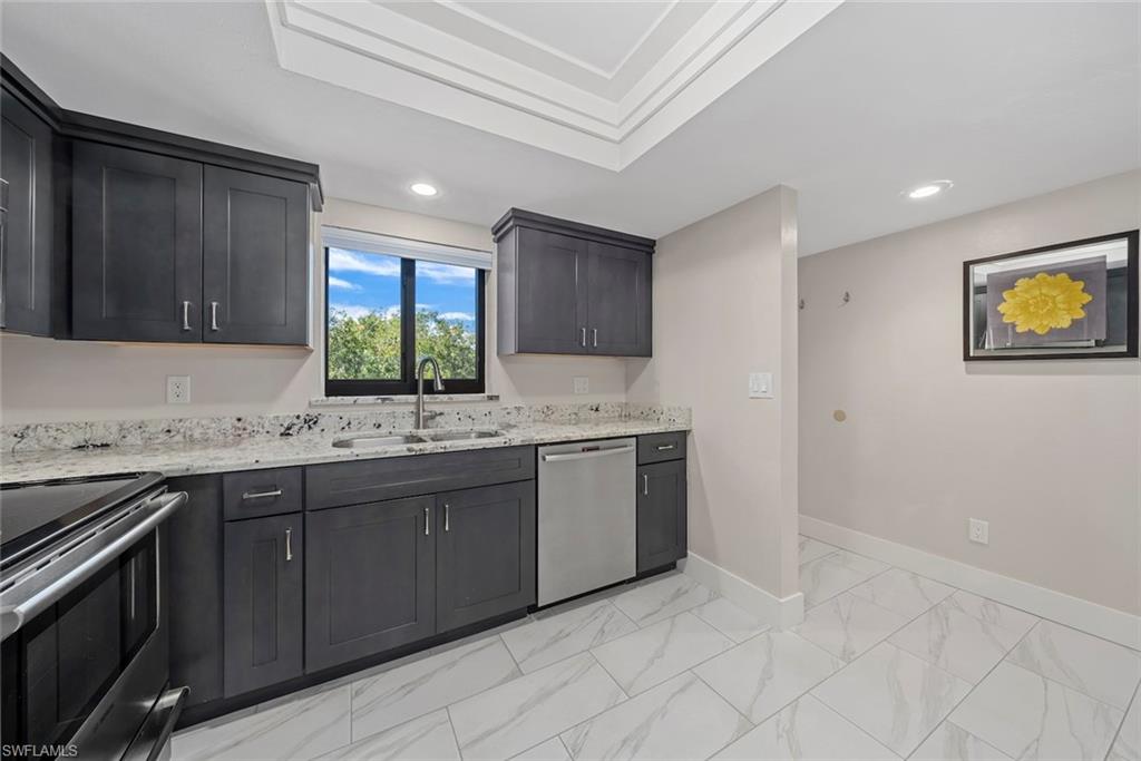 Contemporary kitchen featuring dark wood cabinetry, light speckled countertops, and stainless steel appliances