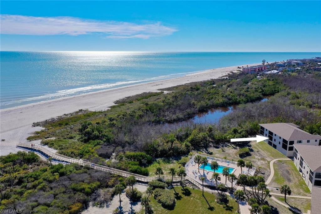 Extensive beachfront property featuring a multi-story building, an outdoor swimming pool, and a boardwalk accessing a wide sandy beach