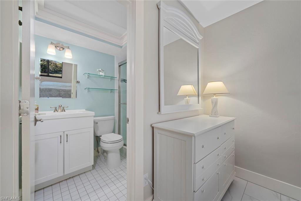 Bathroom featuring a white vanity with integrated sink, chrome faucet, and white tiled flooring