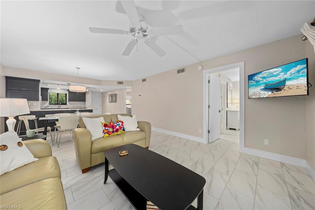 Open-concept living area featuring light-toned walls and wood-finish flooring