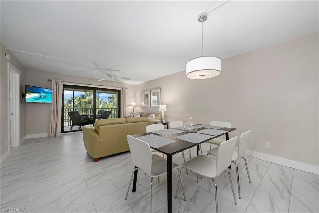 Open-concept living and dining area featuring light-toned walls and wood-finish tile flooring