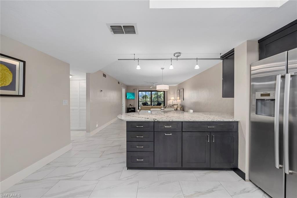 Kitchen island featuring dark wood cabinetry, a light-toned countertop, and stainless steel appliances