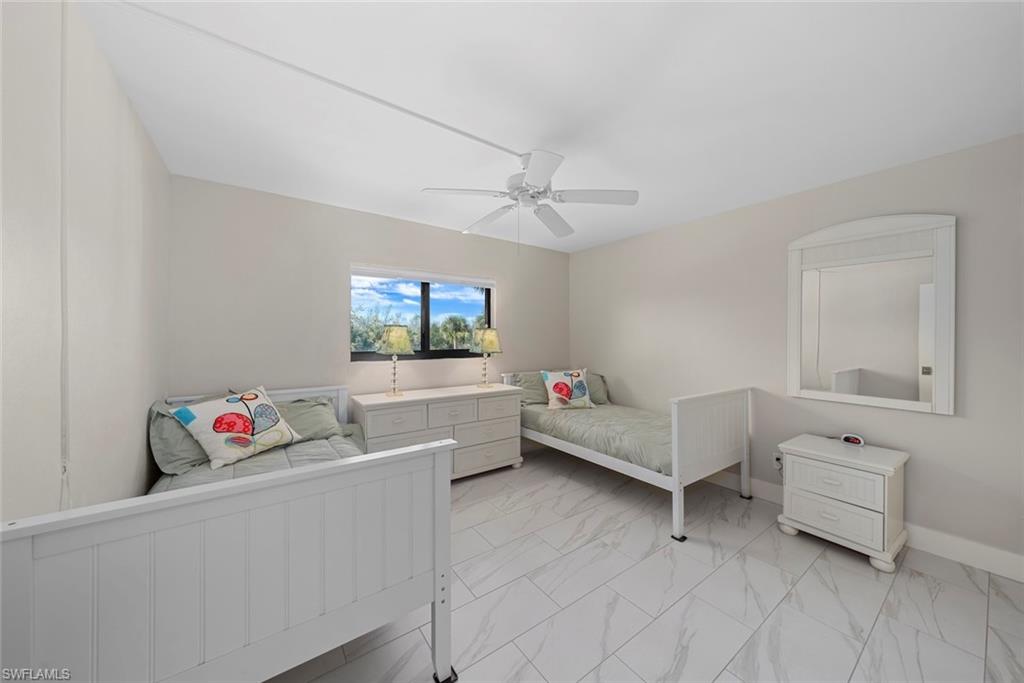 Bright room featuring large format tile flooring, a window offering exterior views, a ceiling fan, and light-toned walls