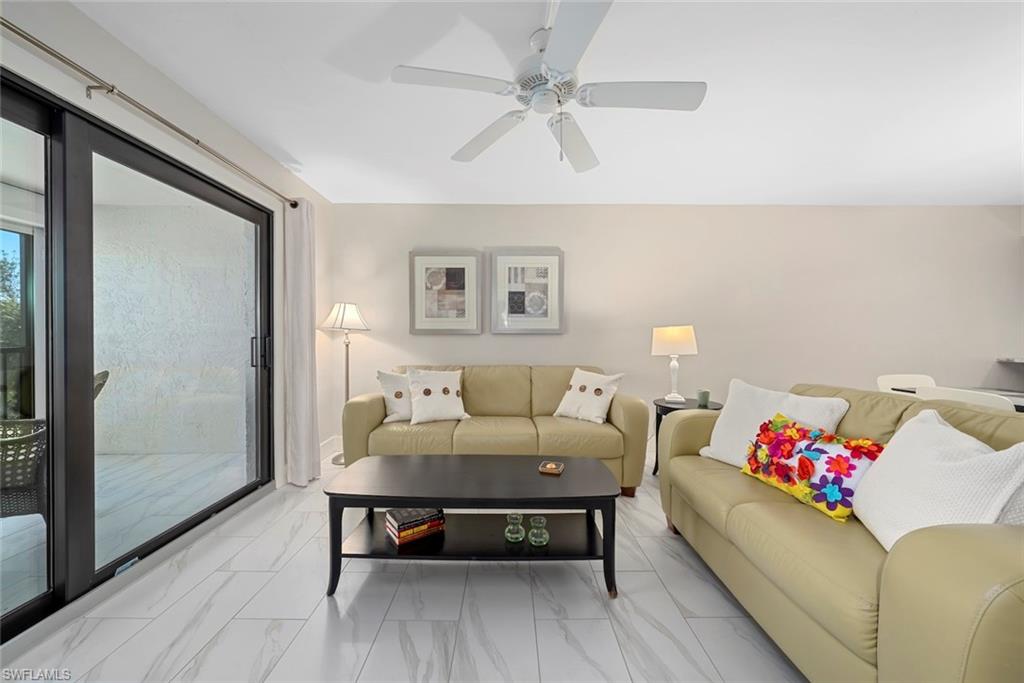 Spacious living area featuring large sliding glass doors, white tile flooring, a ceiling fan, and neutral wall tones
