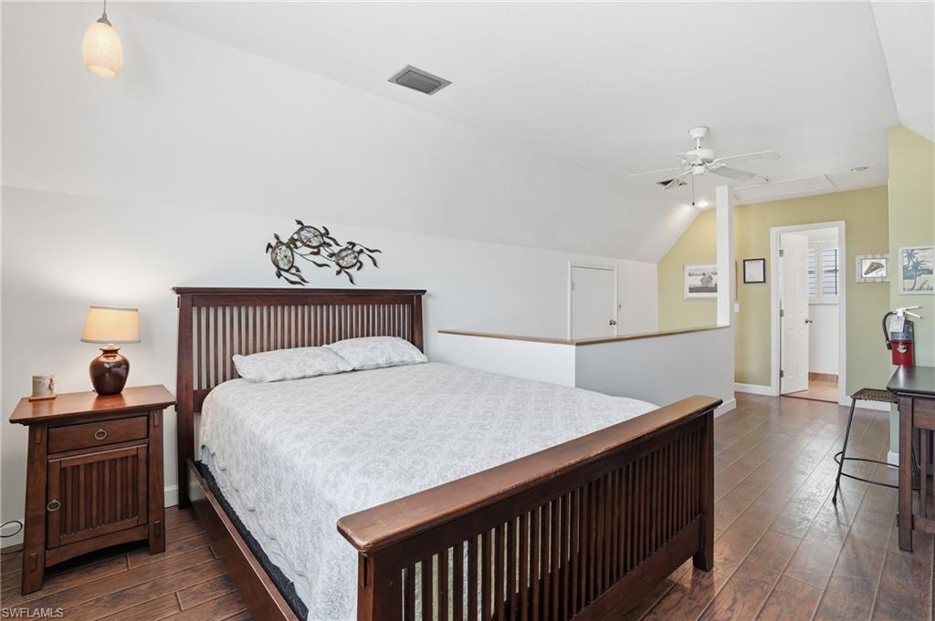 Vaulted ceiling bedroom featuring wood-finish flooring