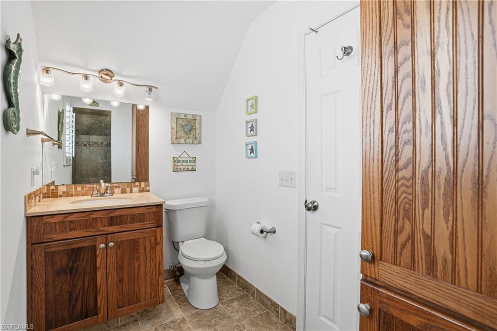 Bathroom featuring a wood-finish vanity with a single sink, an integrated mirror, and a tile backsplash