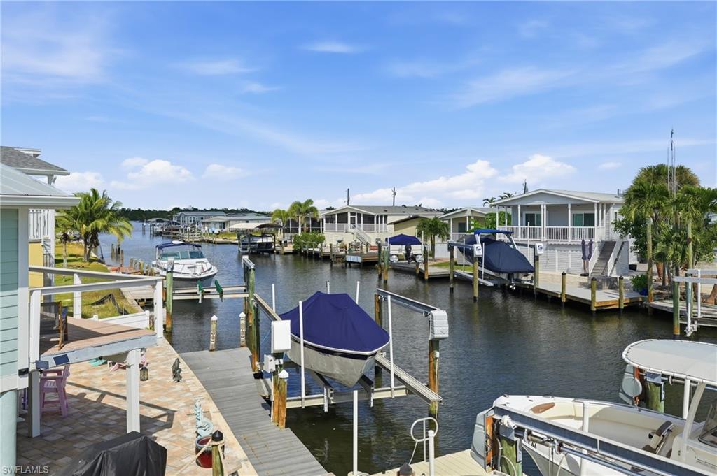 Canal-front property featuring a private boat lift, extensive wooden decking, and mature palm trees