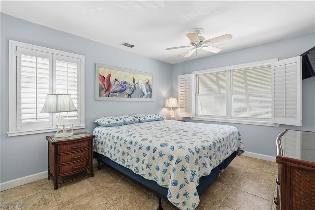 Spacious room featuring two windows with white plantation shutters, a ceiling fan, and tile flooring