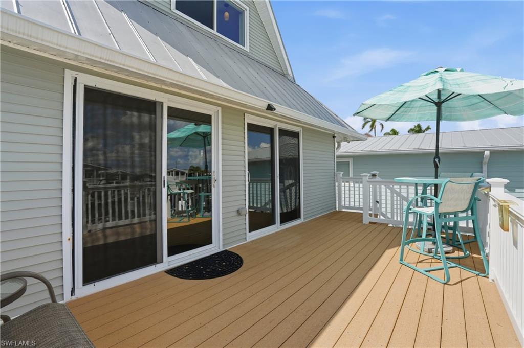 Expansive outdoor deck featuring wood-finish flooring, white railing, and multiple sliding glass doors