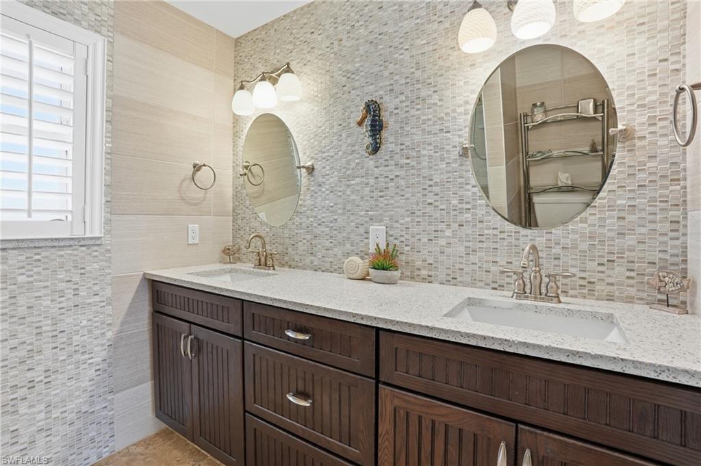 Dual basin vanity featuring dark wood cabinetry, white countertops, and integrated sinks