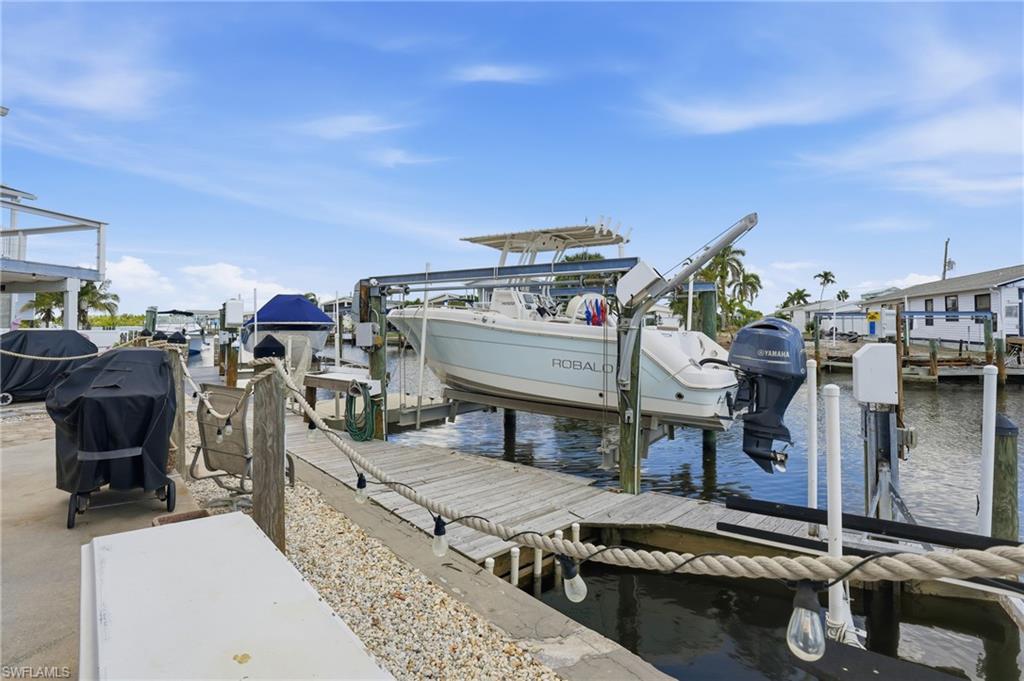 Waterfront property featuring a private boat dock with a boat lift, direct canal access, a concrete patio, and gravel landscaping