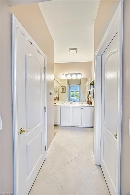 Hallway featuring neutral-toned walls and diamond-patterned tile flooring