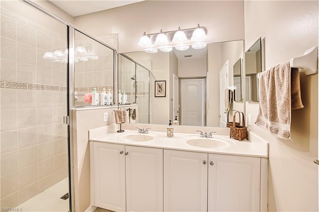 Dual vanity with white cabinetry, integrated sinks, and a large mirror with overhead four-light fixture