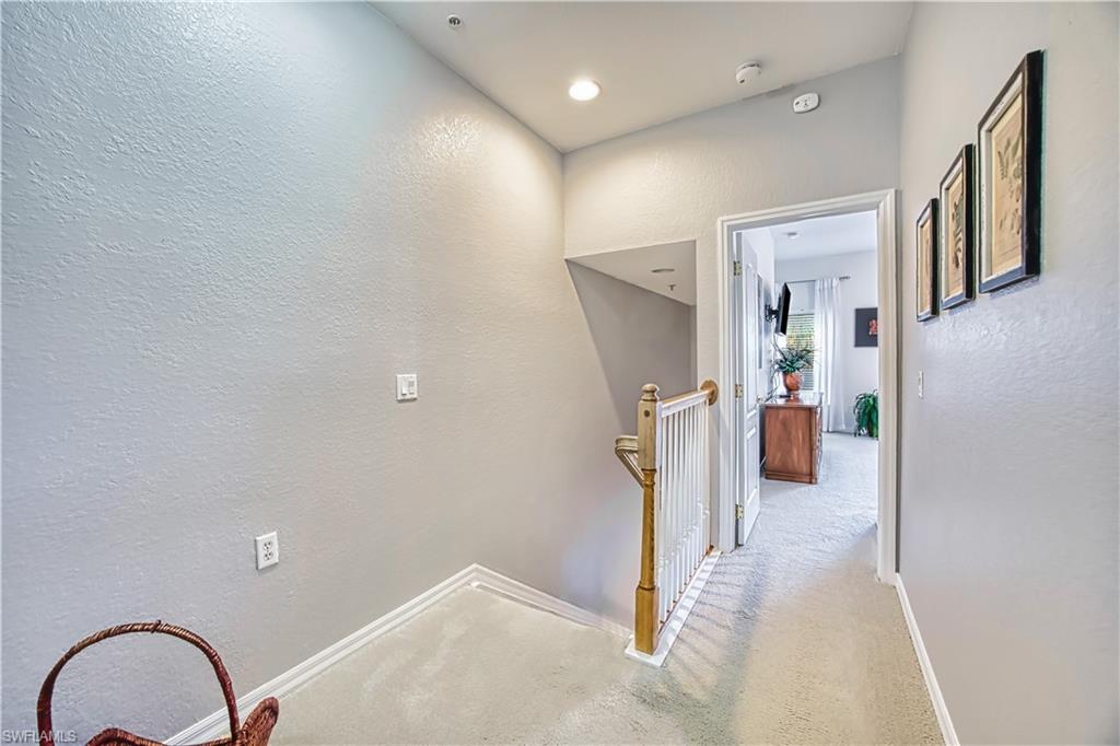 Carpeted hallway with a light wood handrail and white balusters