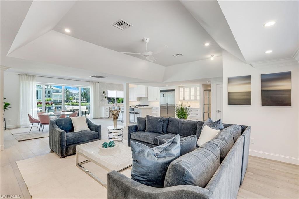 Open-concept living area featuring light wood-finish flooring, recessed lighting, and crown molding