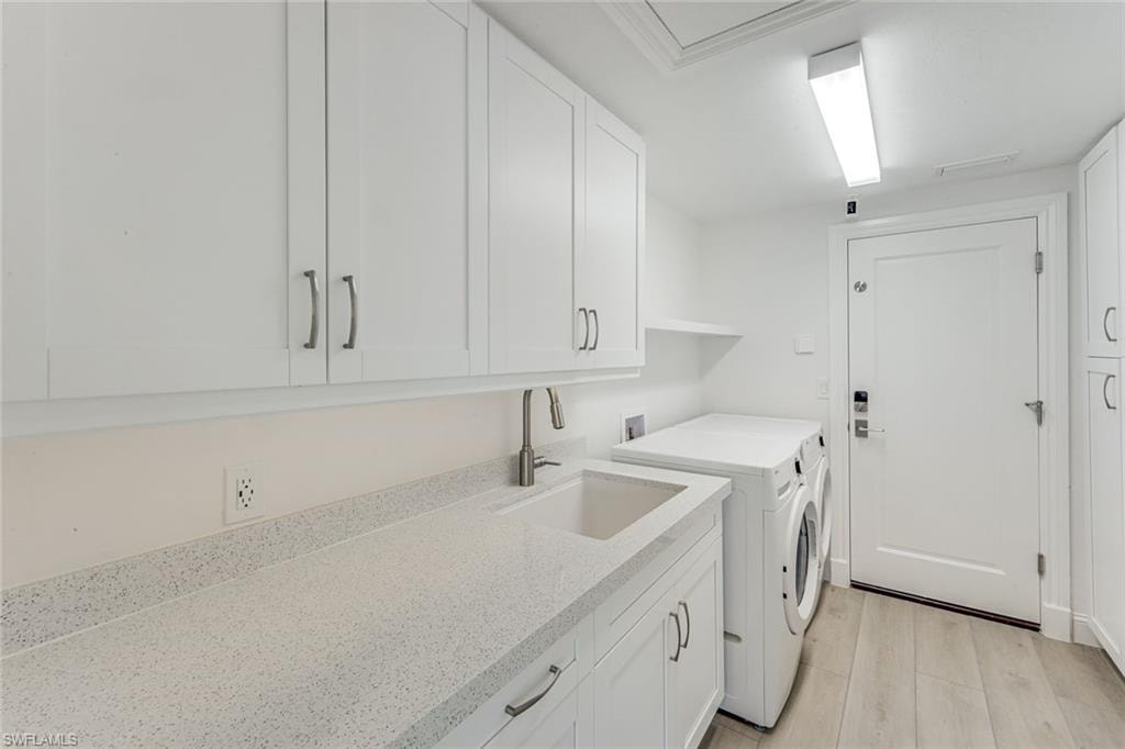 Laundry area featuring white shaker-style cabinetry, a built-in sink, and speckled stone-finish countertops