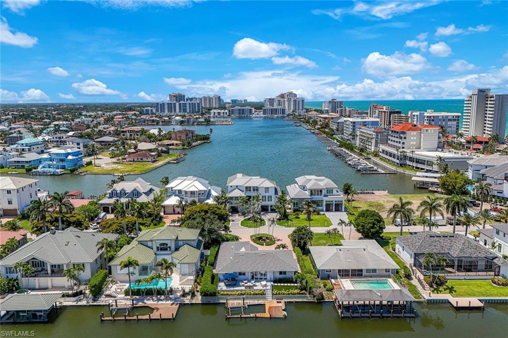 Waterfront community featuring an extensive canal system with private docks, a variety of architectural styles, mature palm trees, and distant high-rise buildings