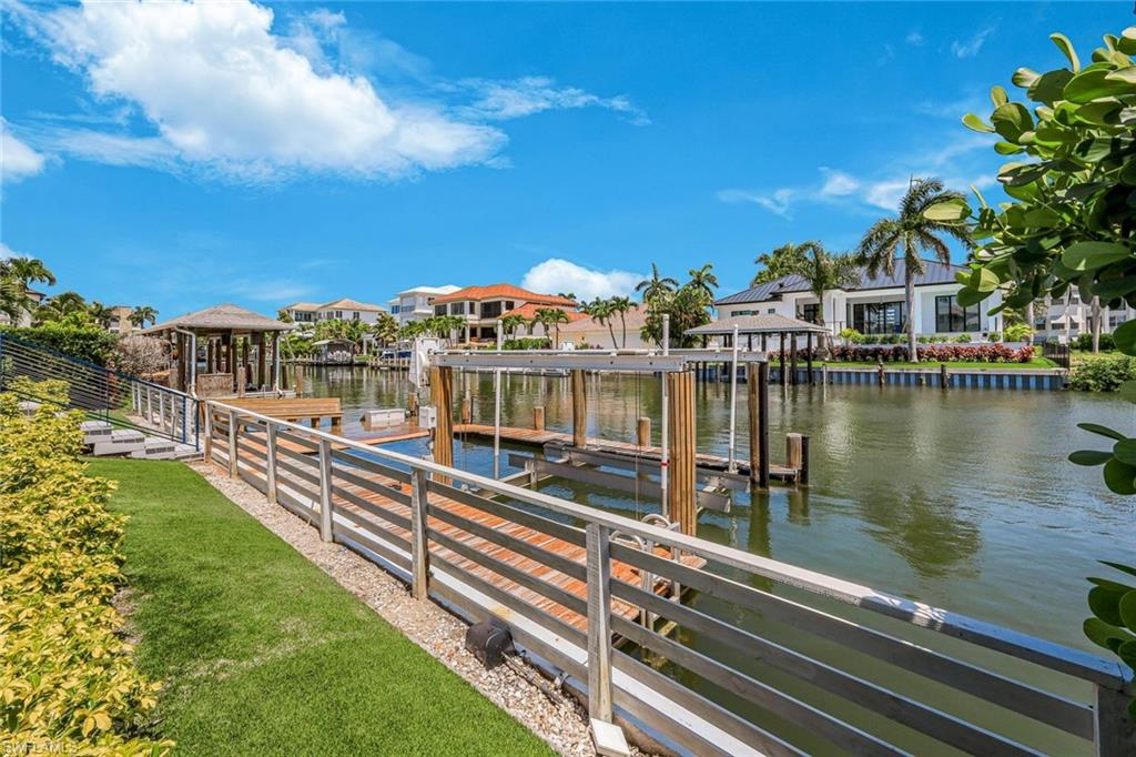 Waterfront dock with a boat lift, a spacious wooden deck, and a privacy fence