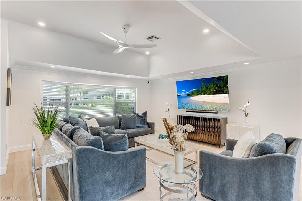 Spacious living area featuring light wood-finish flooring, recessed lighting, and a vaulted ceiling with a white ceiling fan