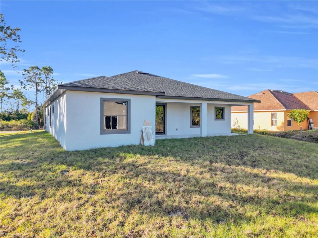 Newly constructed stucco exterior with a dark shingle roof