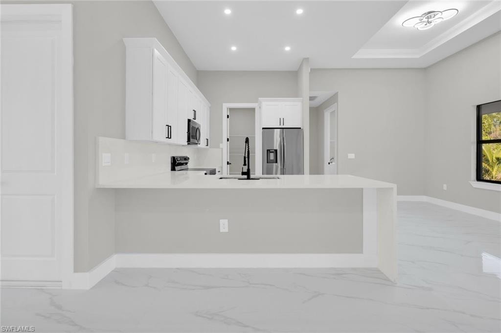 Kitchen island featuring a waterfall edge and integrated sink with a matte black faucet