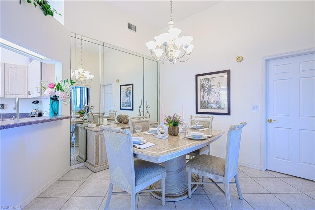 Dining space featuring a chandelier, light tile patterned floors, and a high ceiling