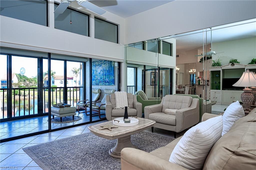 Tiled living room with a ceiling fan, a towering ceiling, and a chandelier
