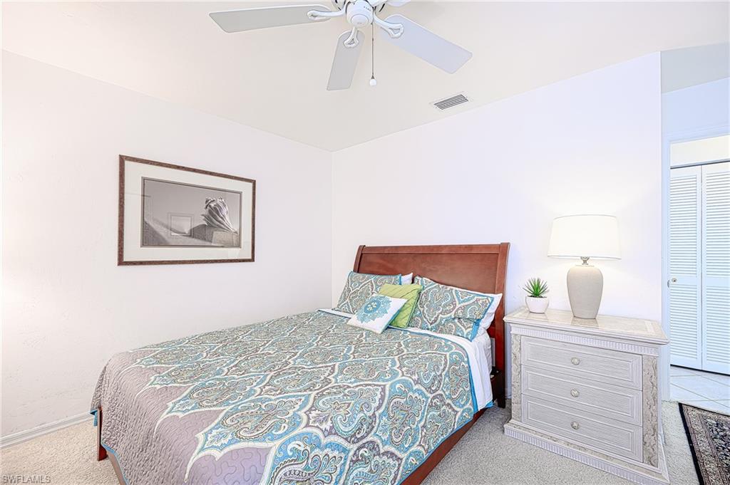 Carpeted bedroom featuring ceiling fan and a closet