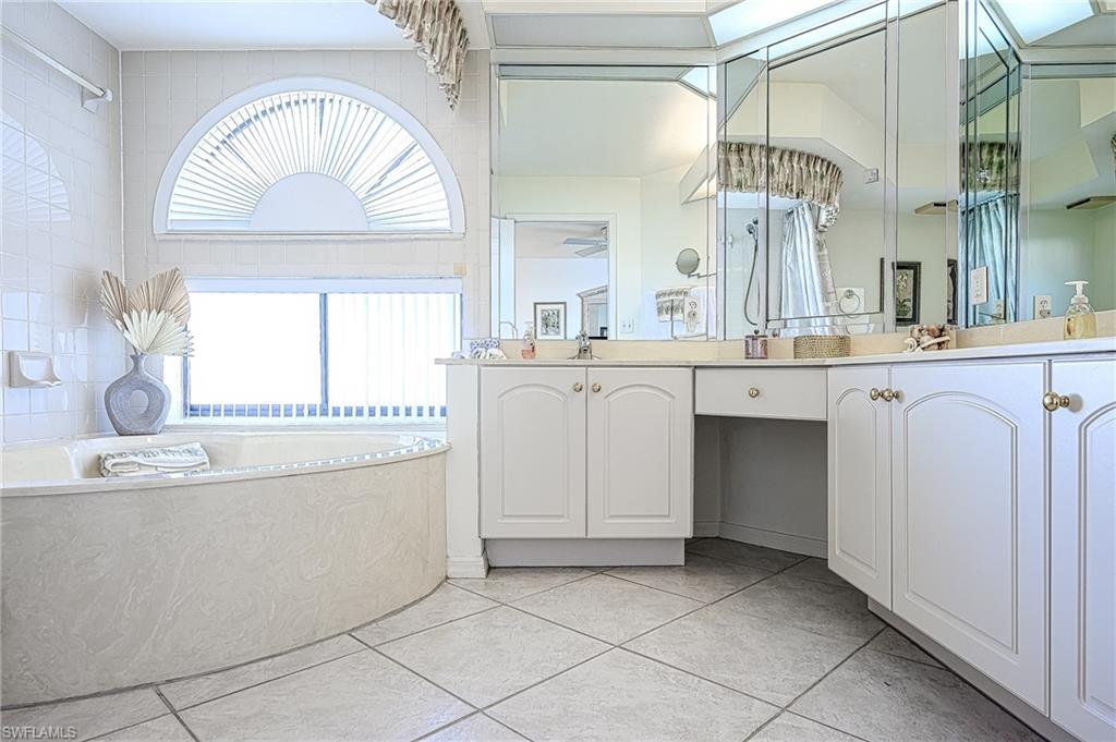 Full bathroom featuring a garden tub, double vanity, and tile patterned flooring