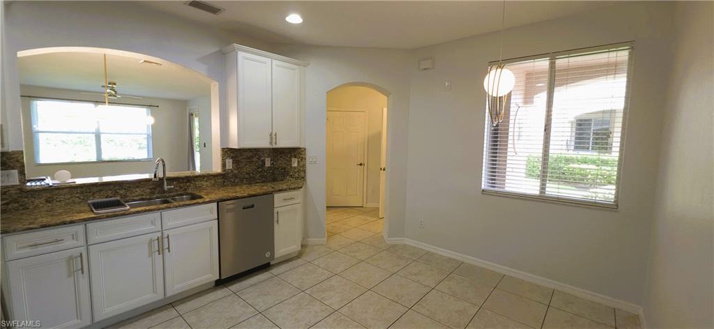 Kitchen featuring white cabinetry, granite countertops with matching backsplash, and a stainless steel dishwasher