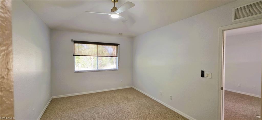 Carpeted interior room featuring a window with blinds, a ceiling fan with integrated lighting, and a neutral wall color