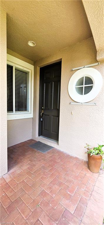 Entryway featuring a dark paneled door, rectangular window with blinds, and a distinctive round accent window