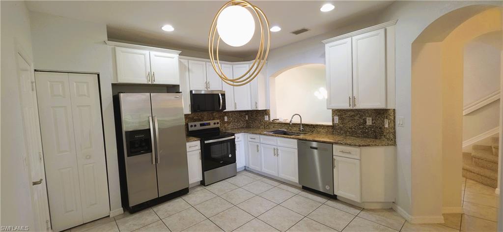Kitchen featuring white cabinetry, granite countertops with matching backsplash, and stainless steel appliances