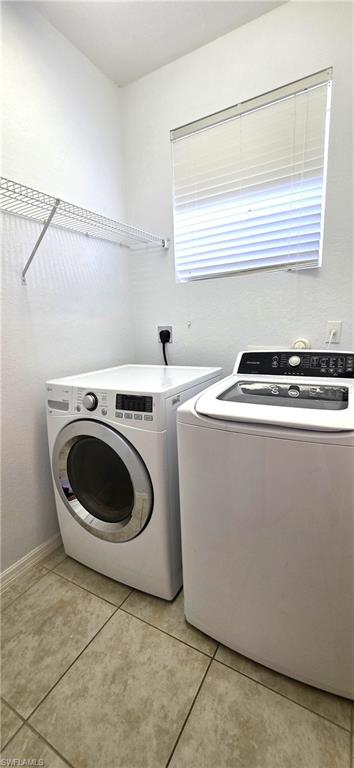 Dedicated laundry area featuring tile flooring, a window with blinds, and a built-in wire shelf