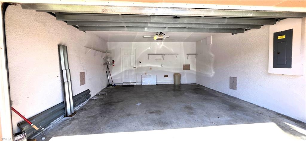 Spacious garage featuring a finished concrete floor, textured walls, overhead garage door mechanism, and a side access door